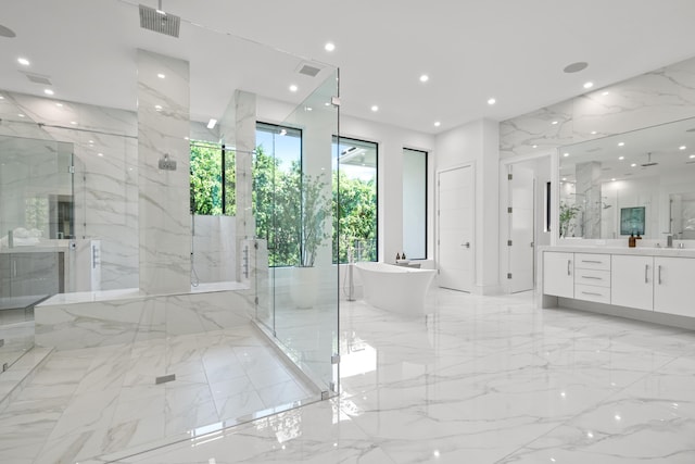 bathroom with recessed lighting, a freestanding tub, visible vents, and stone wall