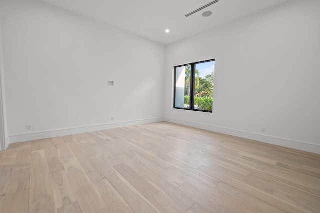 empty room featuring recessed lighting, baseboards, and light wood finished floors