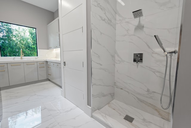 bathroom featuring marble finish floor, a marble finish shower, and vanity