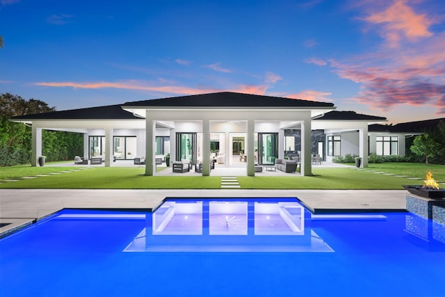 pool at dusk featuring an outdoor pool, a lawn, a patio, and ceiling fan