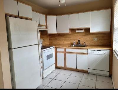 kitchen featuring white cabinets, white appliances, light countertops, and a sink