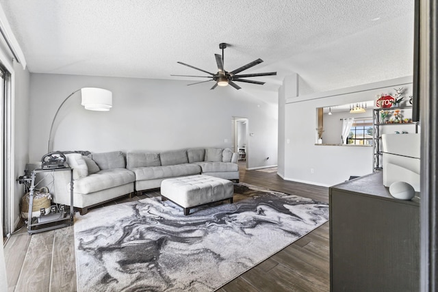 living room featuring baseboards, vaulted ceiling, wood finished floors, a textured ceiling, and a ceiling fan