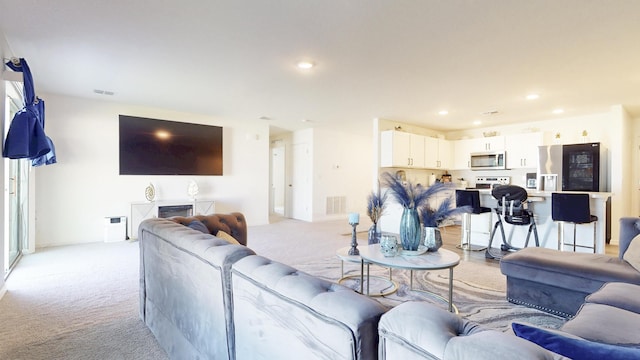 living room with light carpet, visible vents, and recessed lighting