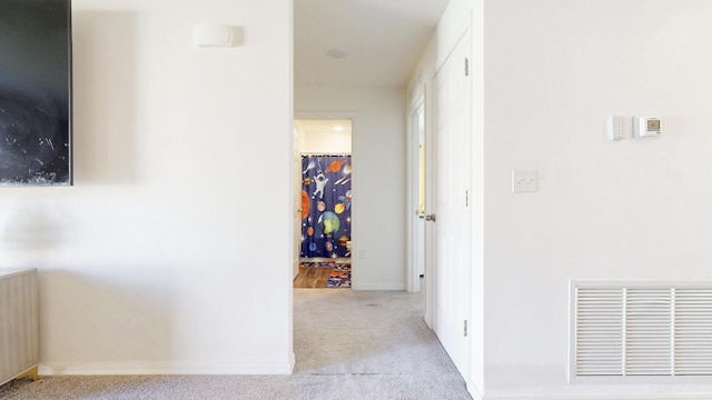 hall with baseboards, radiator heating unit, visible vents, and carpet flooring