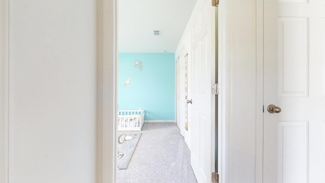 hallway featuring carpet floors, baseboards, and visible vents