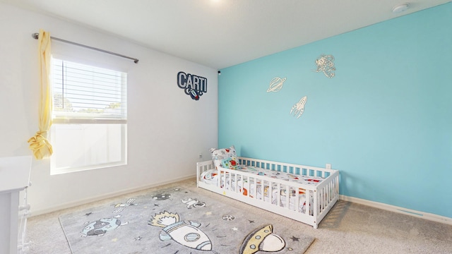 carpeted bedroom featuring a crib and baseboards