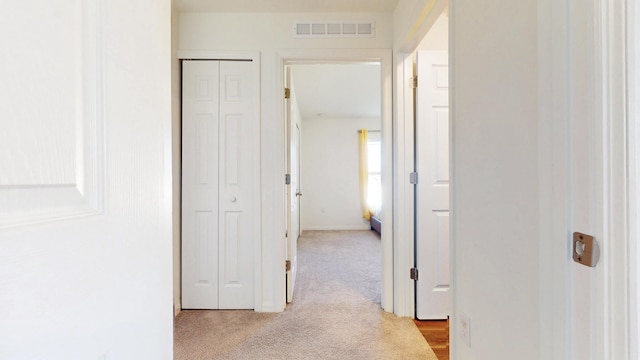 hallway with light colored carpet and visible vents