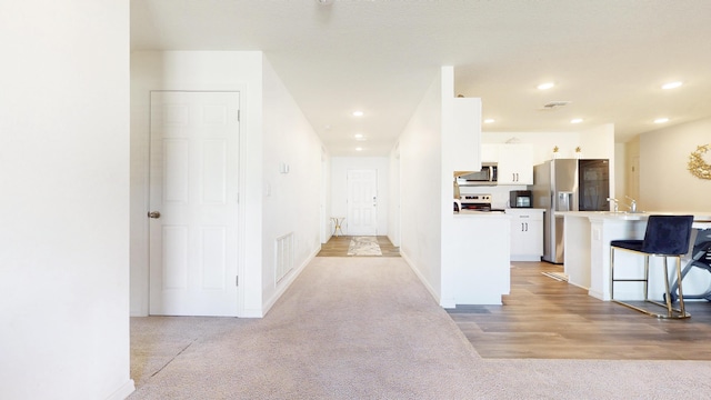 hall with light carpet, baseboards, visible vents, and recessed lighting