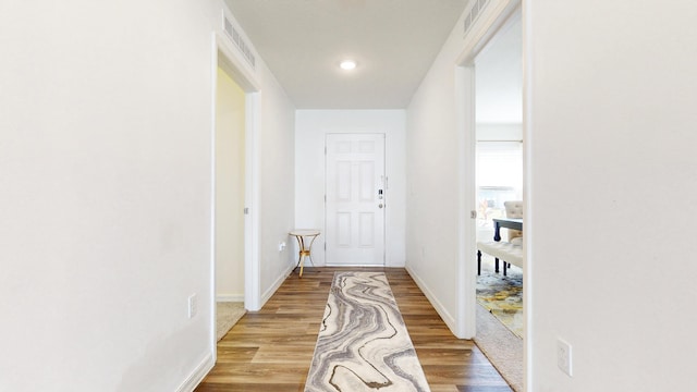 hall with baseboards, visible vents, and light wood-style floors