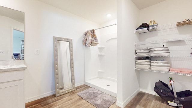 bathroom featuring baseboards, a shower stall, vanity, and wood finished floors