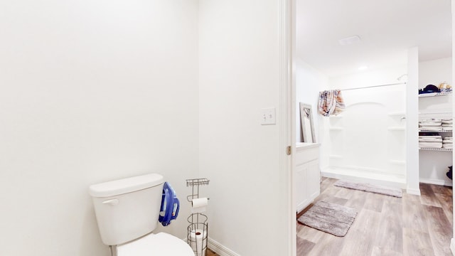 full bath with wood finished floors, baseboards, toilet, and walk in shower