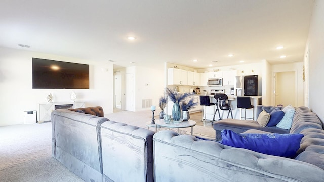 living room with light carpet, visible vents, and recessed lighting