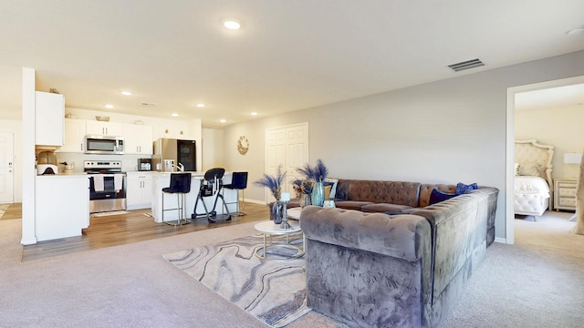 living area with light carpet, visible vents, and recessed lighting