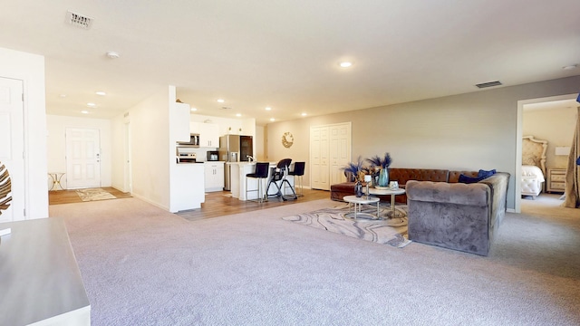 living area with baseboards, recessed lighting, visible vents, and light colored carpet