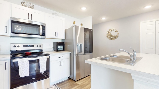 kitchen with stainless steel appliances, light wood-style floors, light countertops, and a sink