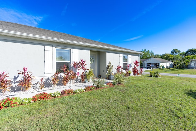 view of front of property with roof with shingles, a front lawn, and stucco siding