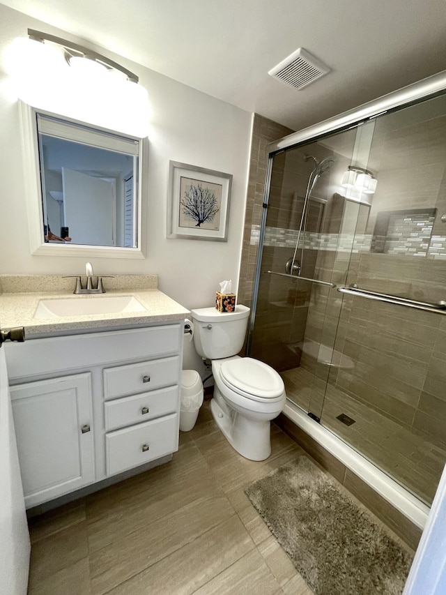 full bath with toilet, a stall shower, vanity, and visible vents