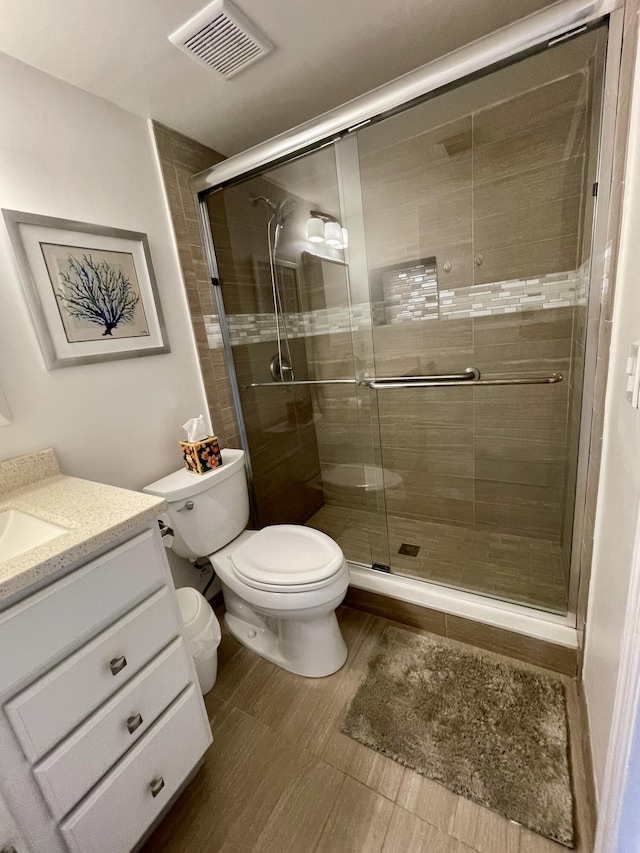 full bathroom with a shower stall, visible vents, vanity, and toilet