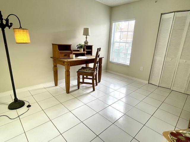 office space with light tile patterned floors, baseboards, and a textured ceiling