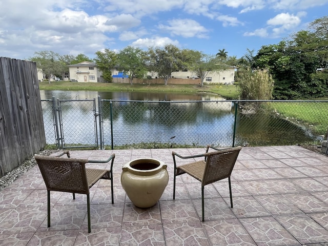 view of patio with a water view, a gate, and fence