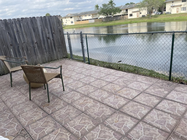 view of patio / terrace featuring a gate, a water view, fence, and a residential view