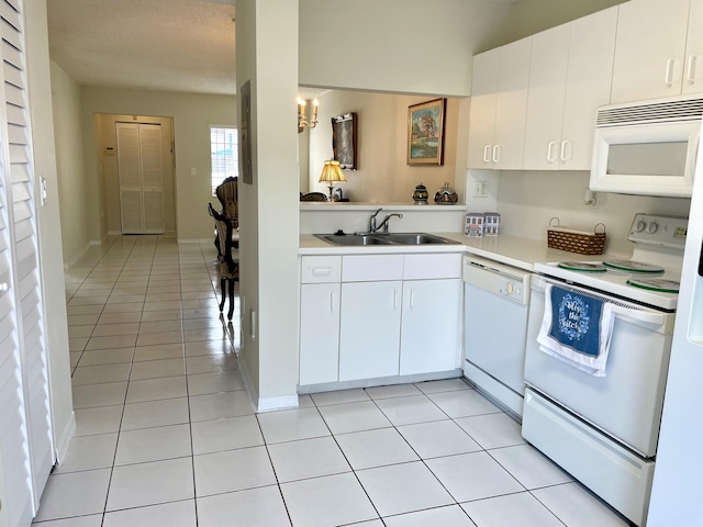 kitchen with white appliances, light tile patterned floors, white cabinets, light countertops, and a sink