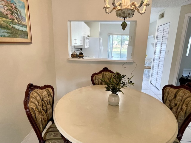 dining room featuring a chandelier, visible vents, and tile patterned floors