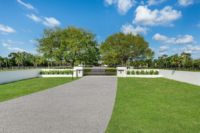 view of property's community with a fenced front yard, a gate, and a lawn