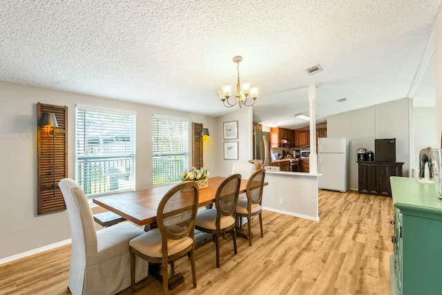 dining area featuring vaulted ceiling, light wood finished floors, a textured ceiling, and an inviting chandelier