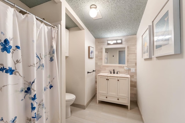 full bathroom with a textured ceiling, toilet, a shower with shower curtain, vanity, and baseboards