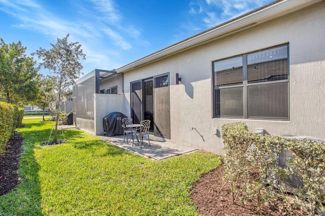 rear view of house with a yard, central AC unit, a patio area, and stucco siding