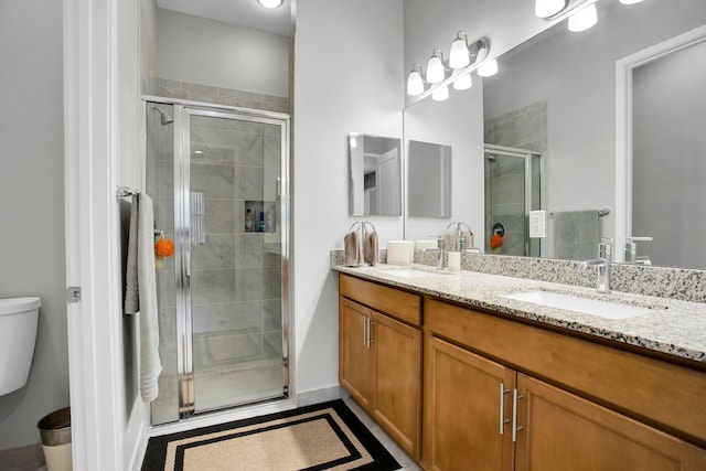 full bathroom with a stall shower, a sink, toilet, and double vanity