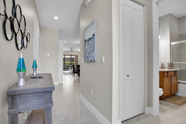 hall featuring recessed lighting, baseboards, and light tile patterned floors