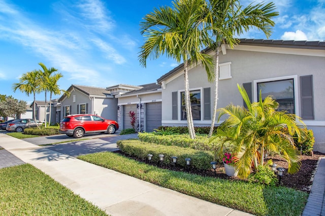 view of front of house featuring a garage, driveway, a residential view, and stucco siding