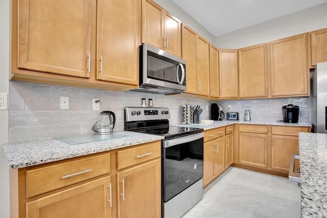 kitchen with appliances with stainless steel finishes, light stone counters, and tasteful backsplash