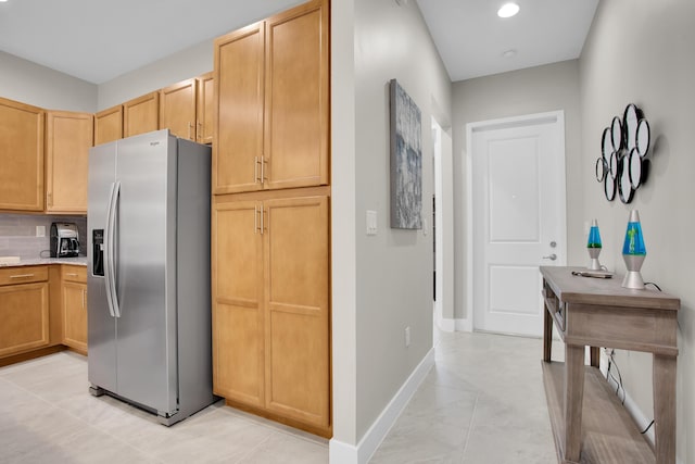 kitchen with light stone counters, recessed lighting, decorative backsplash, stainless steel fridge, and baseboards