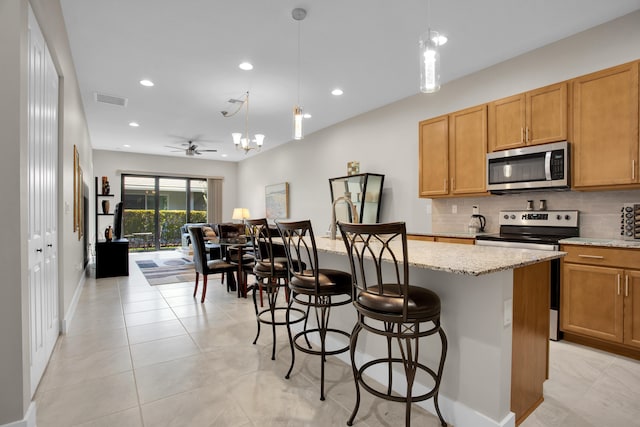 kitchen with visible vents, appliances with stainless steel finishes, decorative backsplash, light stone countertops, and pendant lighting