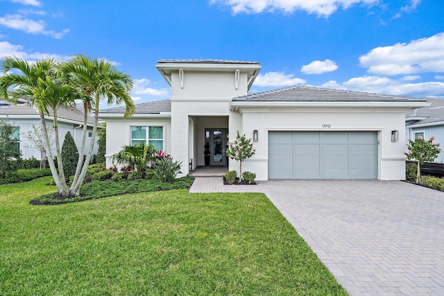 prairie-style home with a front yard, stucco siding, a garage, a tiled roof, and decorative driveway