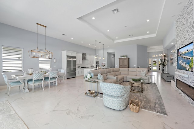 living area featuring a healthy amount of sunlight, visible vents, a towering ceiling, and a chandelier