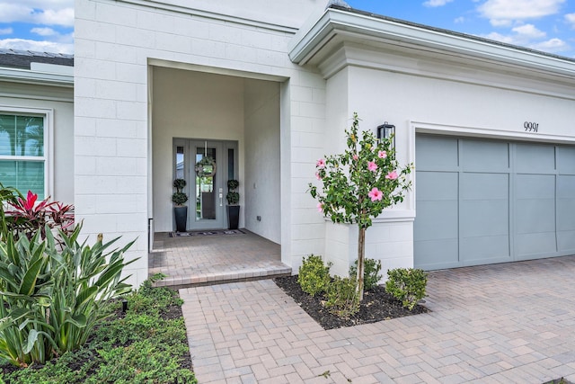 view of exterior entry with decorative driveway, concrete block siding, and an attached garage