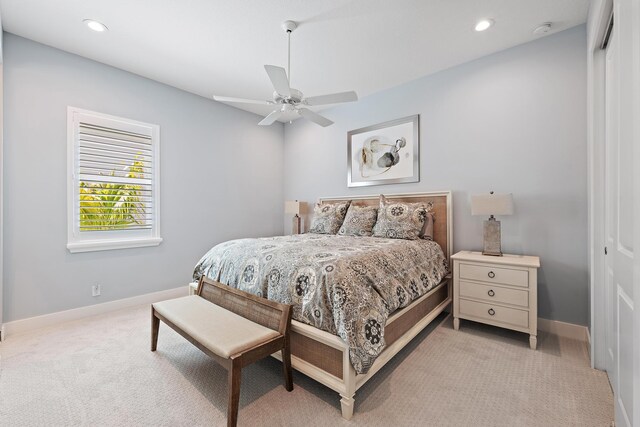 bedroom with a closet, recessed lighting, light colored carpet, and baseboards