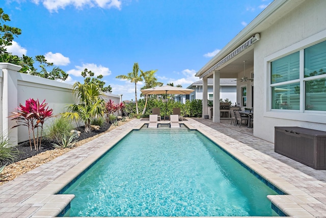 outdoor pool featuring a patio area, fence, and ceiling fan