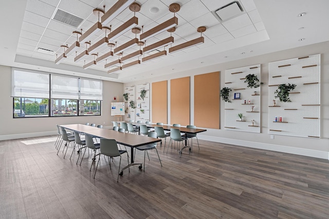 dining room featuring visible vents, a raised ceiling, baseboards, and wood finished floors