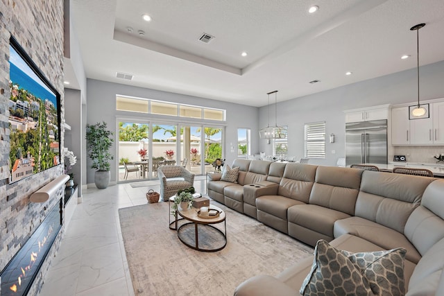 living area featuring a tray ceiling, visible vents, marble finish floor, and recessed lighting