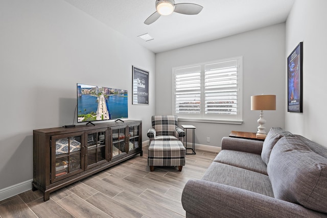 living room featuring ceiling fan, baseboards, and wood finished floors