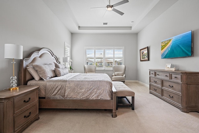 bedroom featuring visible vents, light carpet, a ceiling fan, a tray ceiling, and baseboards