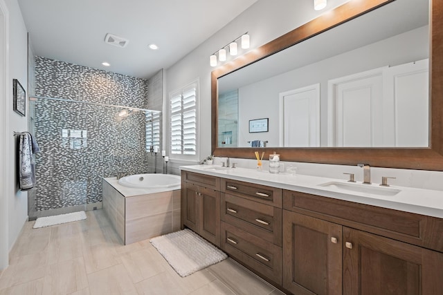 bathroom featuring double vanity, a garden tub, a tile shower, and a sink