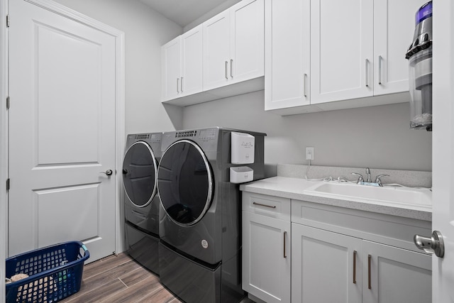 washroom with a sink, cabinet space, separate washer and dryer, and wood finished floors