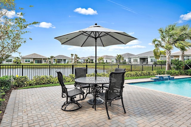 view of swimming pool with a patio, a fenced in pool, fence, a water view, and a residential view