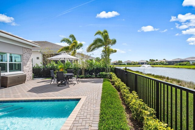 view of pool with a patio area, a fenced in pool, fence, and a water view